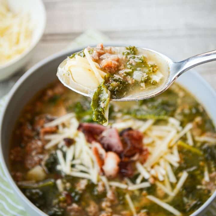 A bowl of zuppa toscana, with a spoonful of soup.