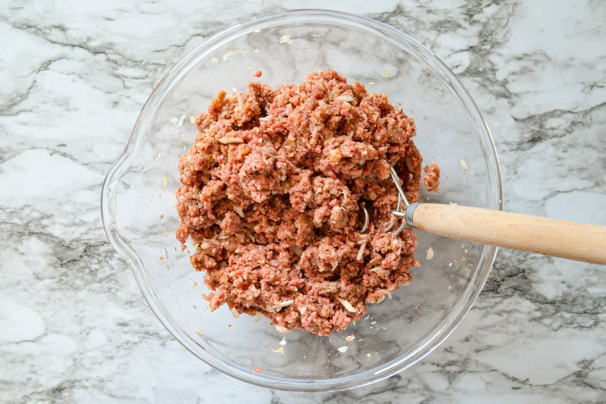 A bowl of mixed meat and seasonings to make whole food freezer meatballs.