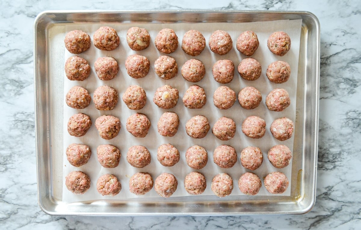 A sheet pan of prepared and rolled meatballs.