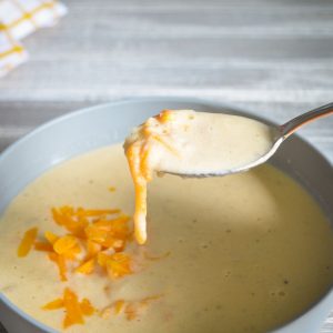 A bowl of soup with stretchy cheese.