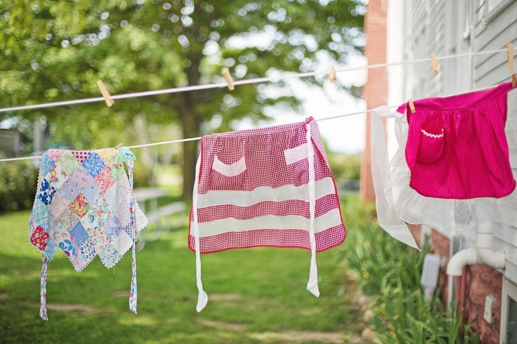 3 Vintage aprons, hanging on an outdoor clothesline.