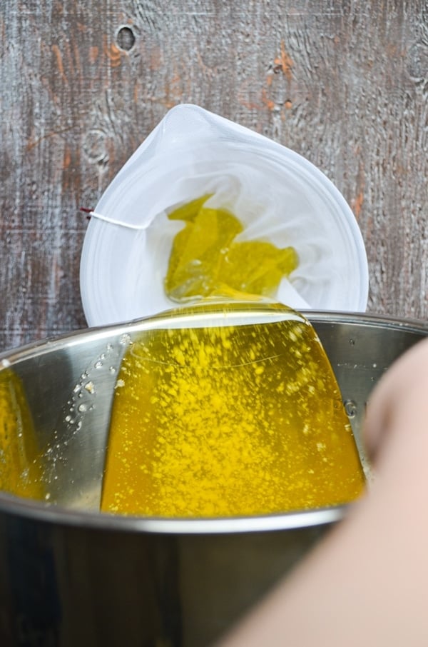 Pouring off the clarified butter through a nut milk bag to further remove the milk solids.