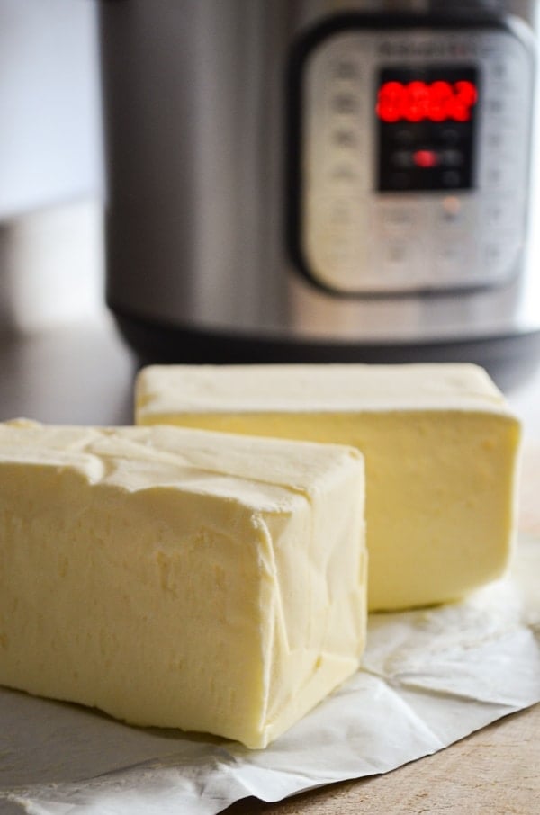 Two pounds of butter, laying on their wrapper, with an Instant Pot in the background.