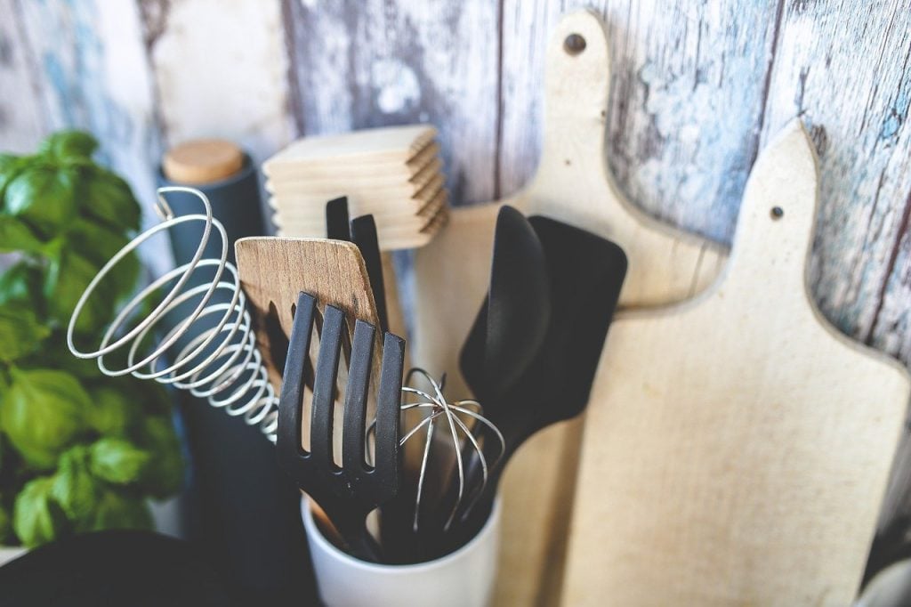 Wooden cutting boards and utensils, against a backdrop of wood.