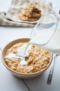 Milk being poured on a bowl of peanut butter cookie oatmeal.