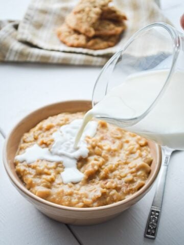 Milk being poured on a bowl of peanut butter cookie oatmeal.