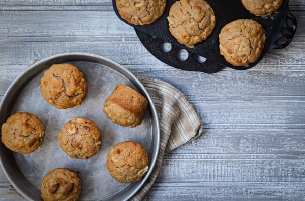 A cast iron muffin pan, as well as small cake pan, full of sourdough muffins.