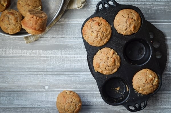 A cast iron muffin pan, holding 4 sourdough muffins.