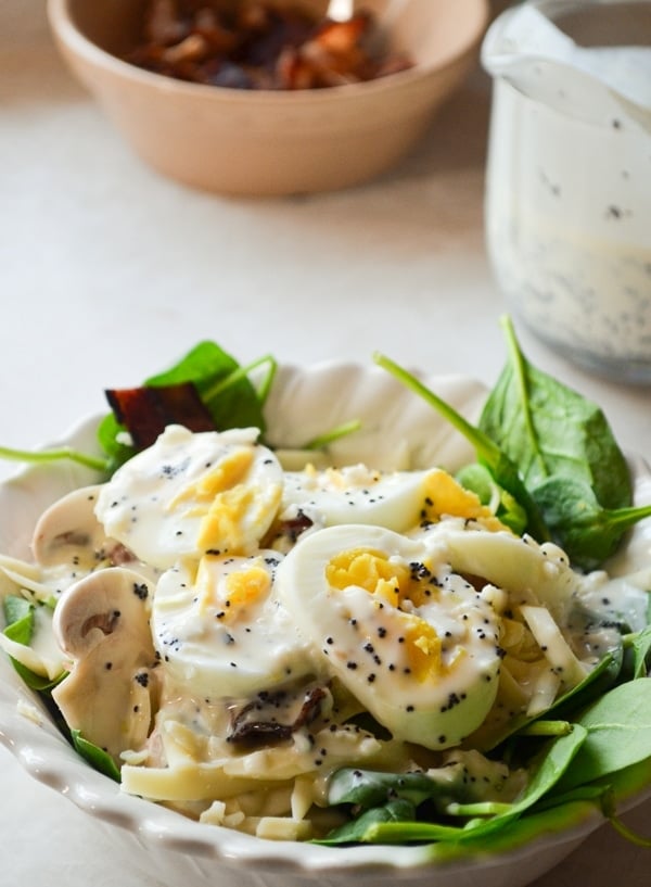 A bowl of spinach salad, drizzled with Healthy Poppy Seed Salad Dressing