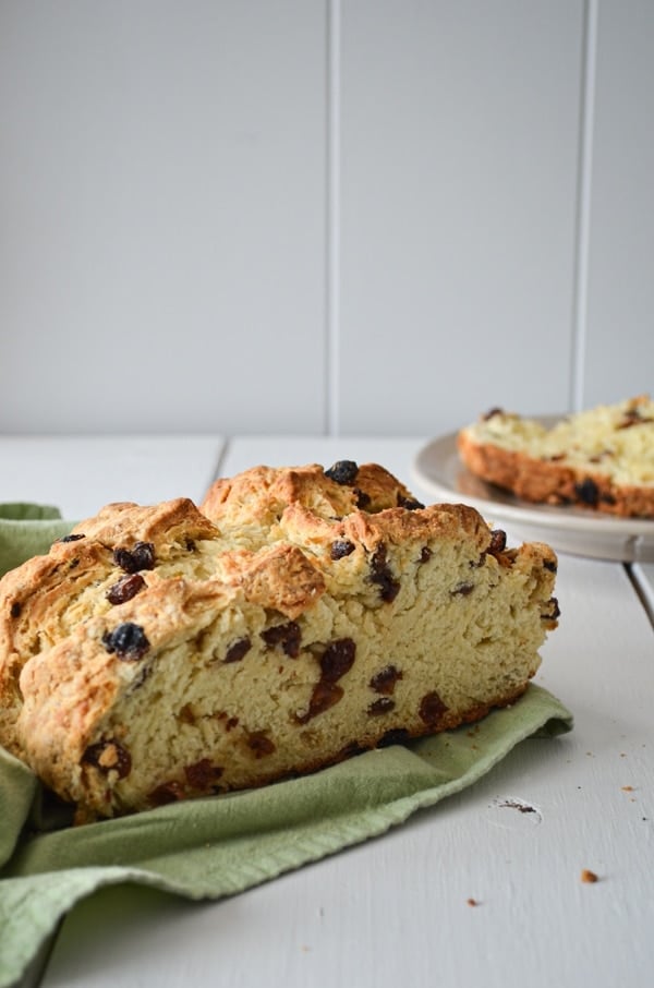 A loaf of sourdough discard Irish Soda bread, speckled with raisins and resting on a green cloth napkin.