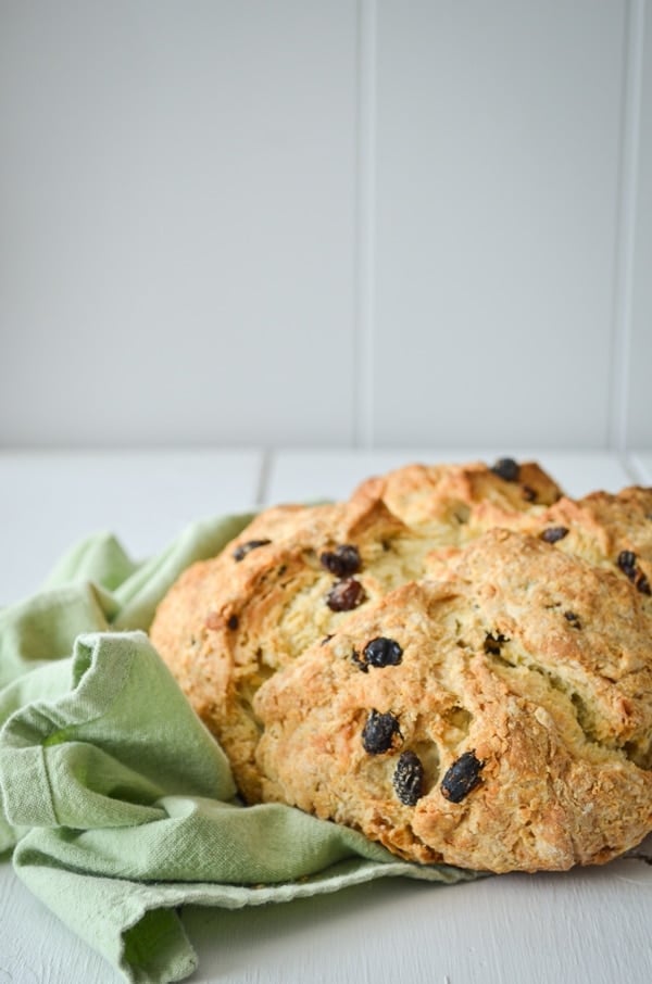 A loaf of sourdough discard Irish Soda bread, speckled with raisins and resting on a green cloth napkin.