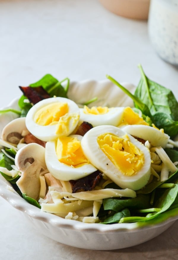 A small bowl of baby spinach salad, topped with hard-boiled eggs.