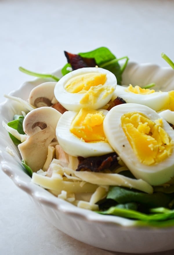 A small bowl of baby spinach salad, topped with hard-boiled eggs.