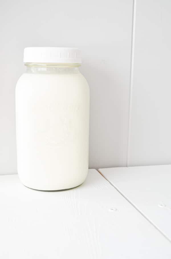 A jar of buttermilk cultured milk sits at the back of a table.