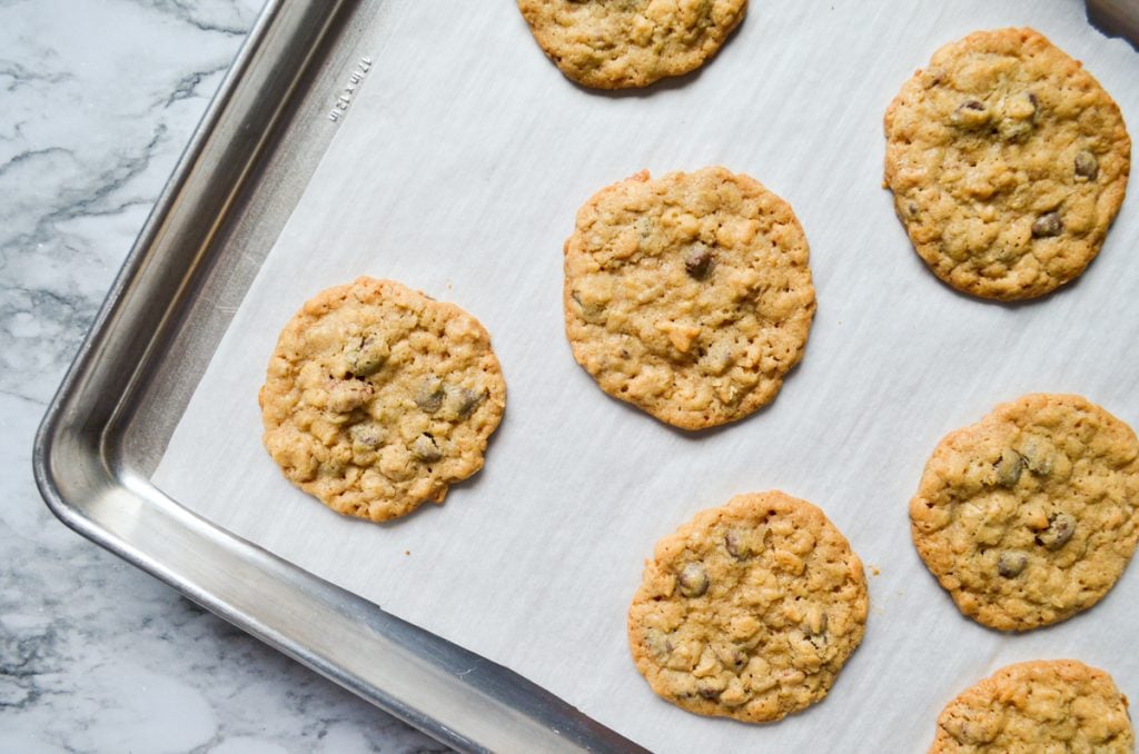 An overhead view of a baking sheet with baked cookies on parchment paper.