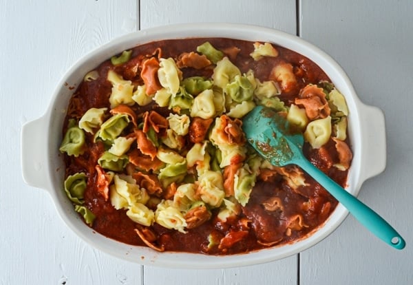 A baking dish is filled with tortellini and pasta sauce.