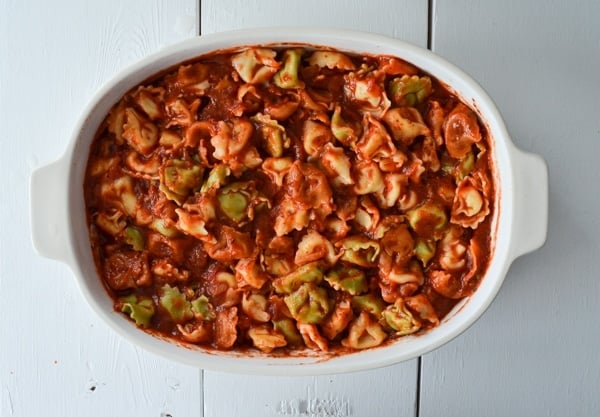 A baking dish is filled with tortellini and pasta sauce.
