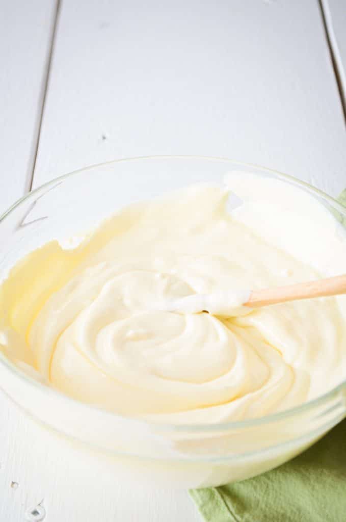 A bowl of cultured creme fraiche is stirred.