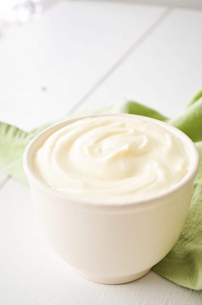 A small crock of Creme fraiche, placed on a green napkin.