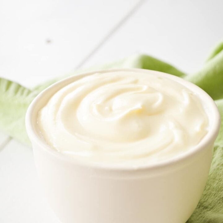 A small crock of Creme fraiche, placed on a green napkin.