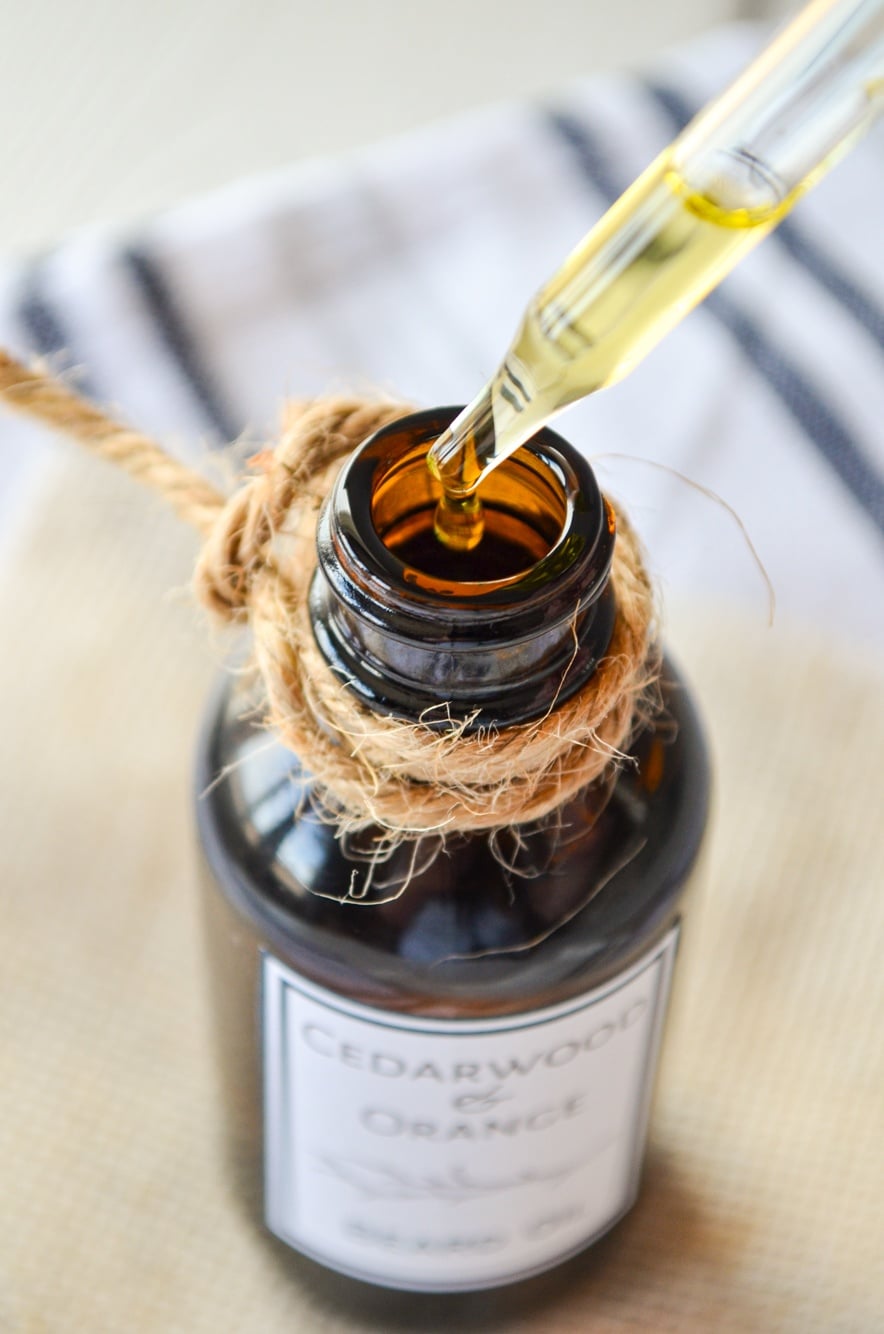 An oil dropper at the top of an amber bottle of beard oil. A bit of twine wrapped around the top.