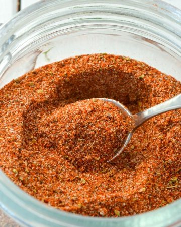 A jar of spices with a spoon in it.