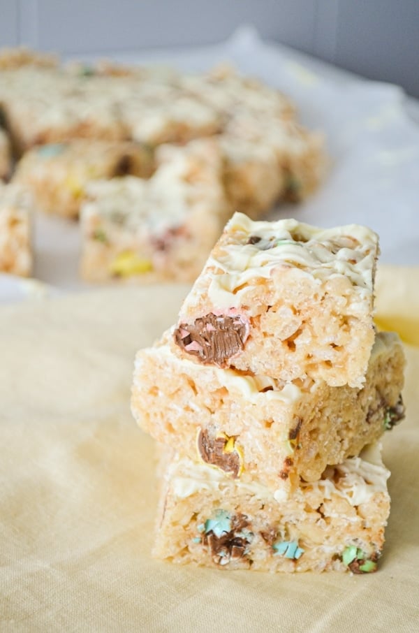 Three rice krispie treats stacked on top of one another. They are filled with mini eggs.