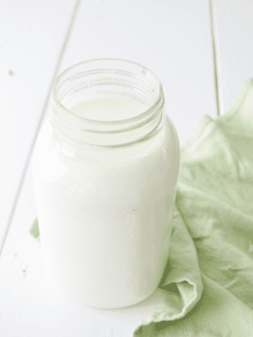 A jar of cultured buttermilk, resting on a green cloth napkin.