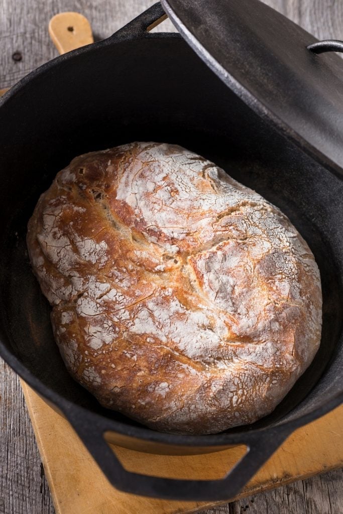 A dutch oven with a loaf of bread inside.