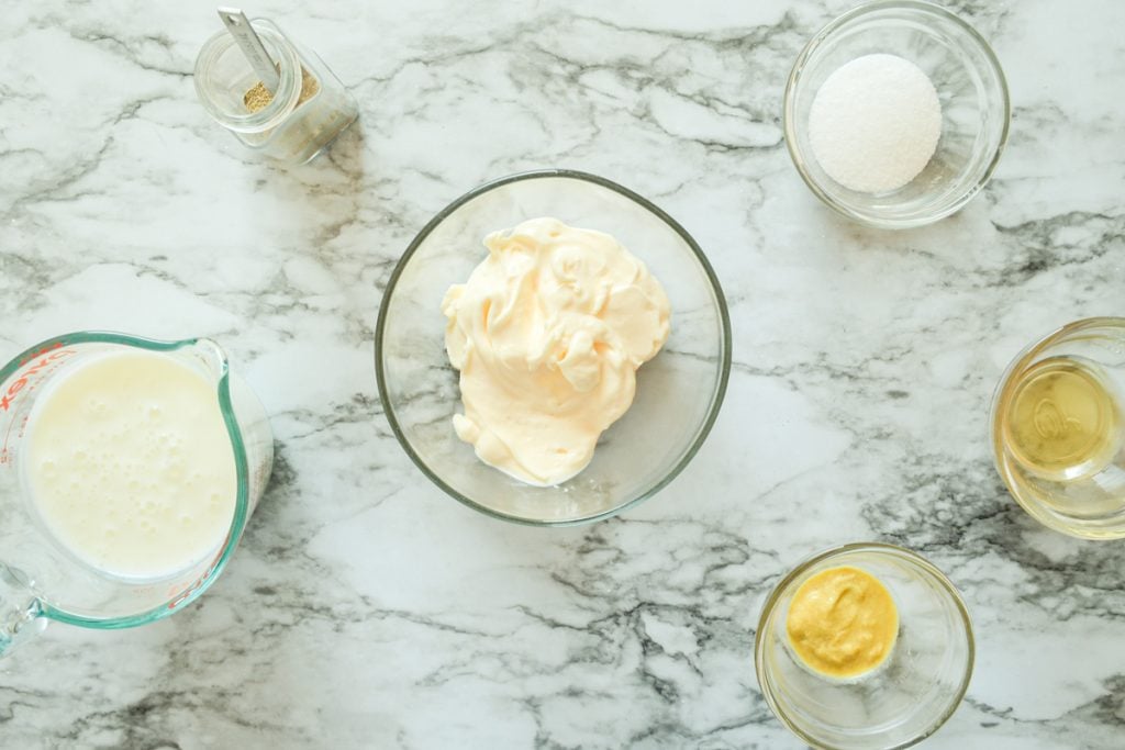 An overhead view of the ingredients needed, including mayonnaise, buttermilk, spices, sugar, and mustard.