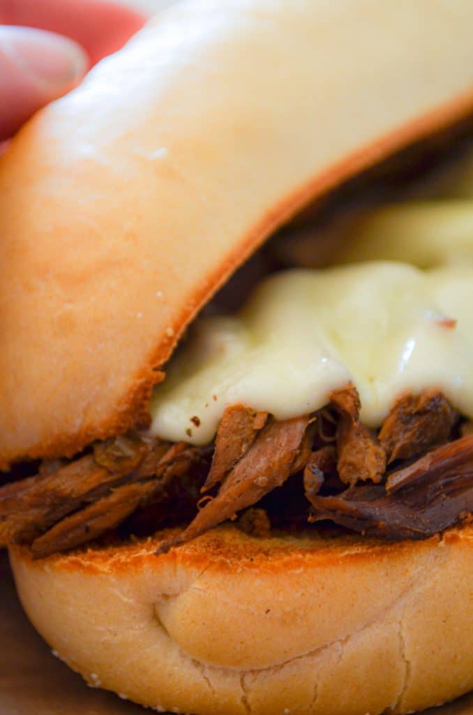 A close up of a french dip sandwich with melted provolone cheese.