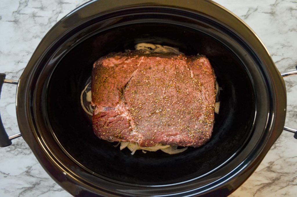 A crockpot with a seasoned beef roast inside. Soon, it will be shredded meat for French Dip sandwiches.