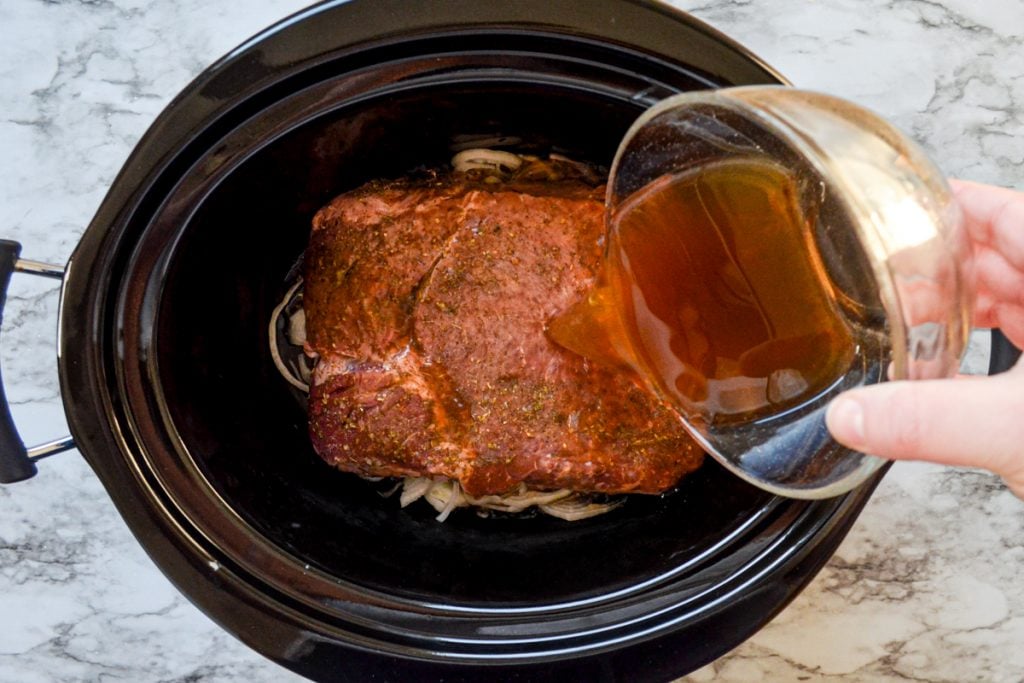 Beef broth is poured over the beef and onions