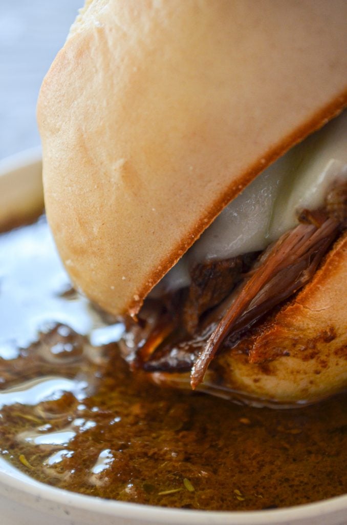 A french dip sandwich bening dipped into homemade au jus.