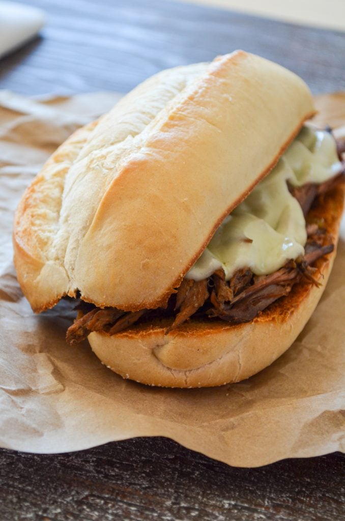 A french dip sandwich, resting on some brown paper. 