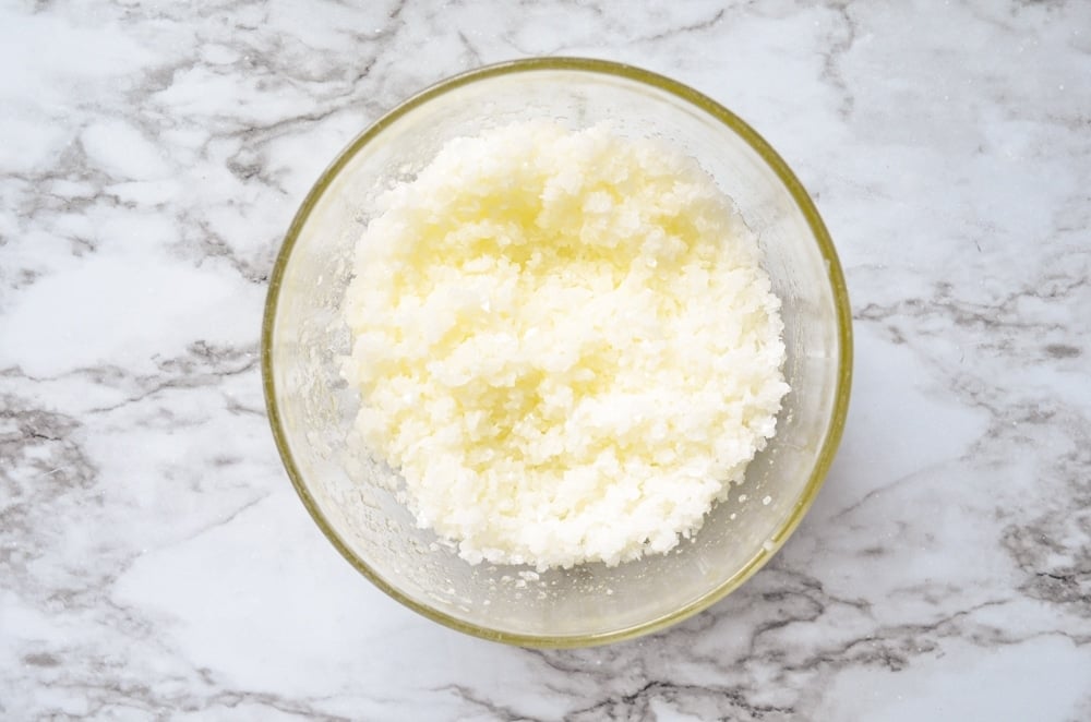 An overhead view of a combination of salt, orange essential oil, coconut oil, and jojoba oil. This combination makes a facial salt scrub.