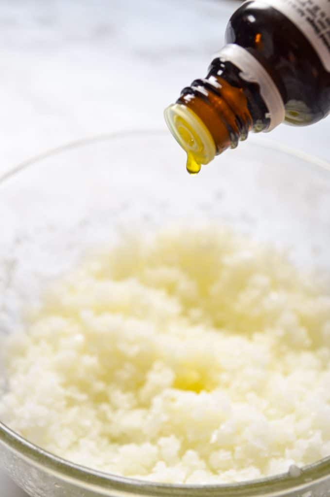 Orange essential oil being dropped into a homemade facial salt scrub