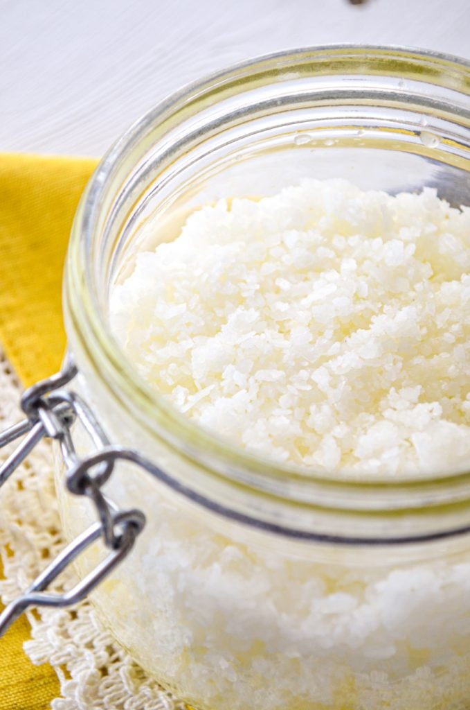 A jar of facial salt scrub, resting on a bright yellow napkin.