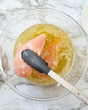 Chicken breasts being marinated in a pickle juice based marinade.