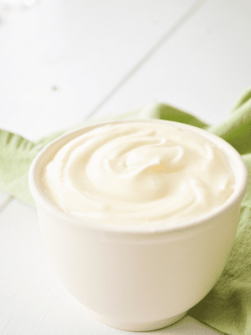 A small crock, filled with crème fraiche and resting on a green napkin. The text reads: How to make crème fraiche.