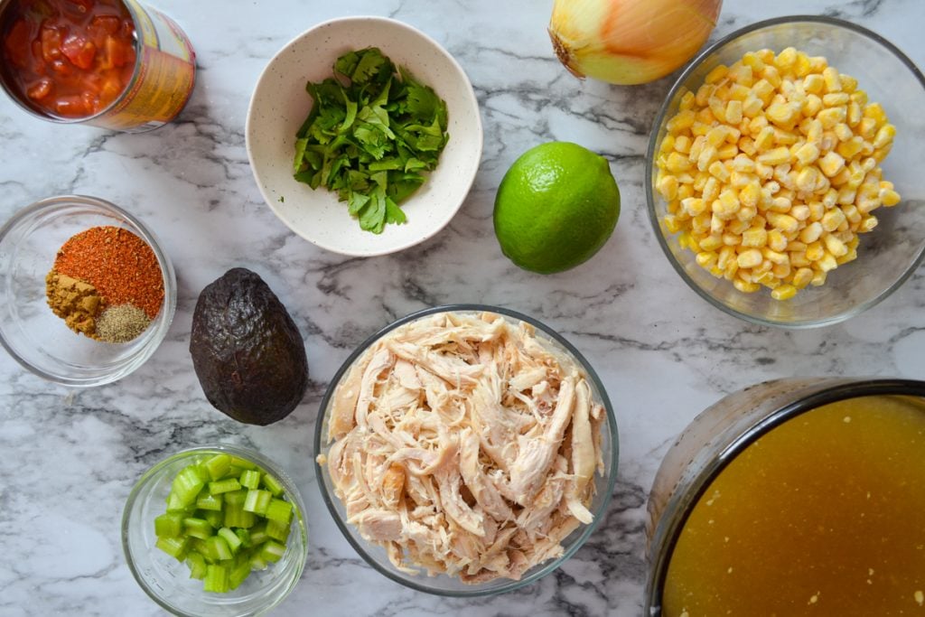 The ingredients needed for Mexican Chicken soup: chicken broth, cooked and shredded chicken, corn, cilantro, lime, onion, celery, rotel, and seasonings to name a few.