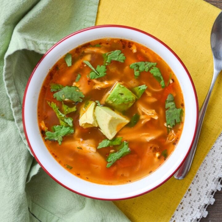 A bowl of healthy mexican chicken soup, resting on a yellow napkin.