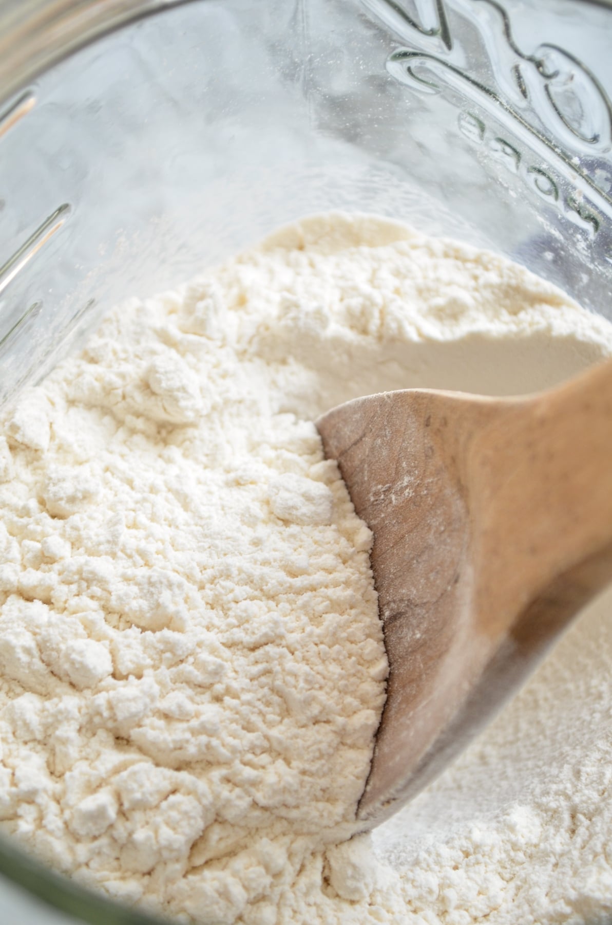 Flour in a large glass canister with a wooden spoon in it.