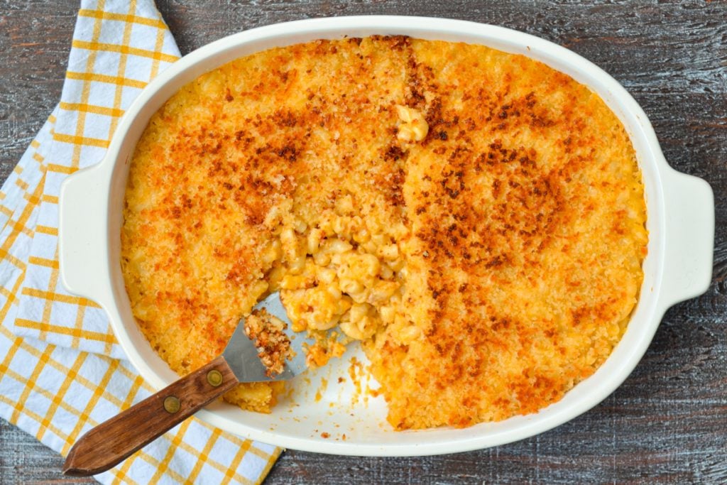 A macaroni and cheese casserole in a baking dish, with a portion removed.