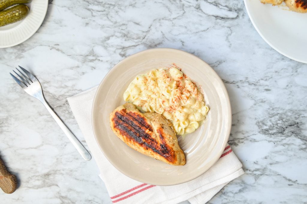 Grilled chicken on a plate with macaroni salad.