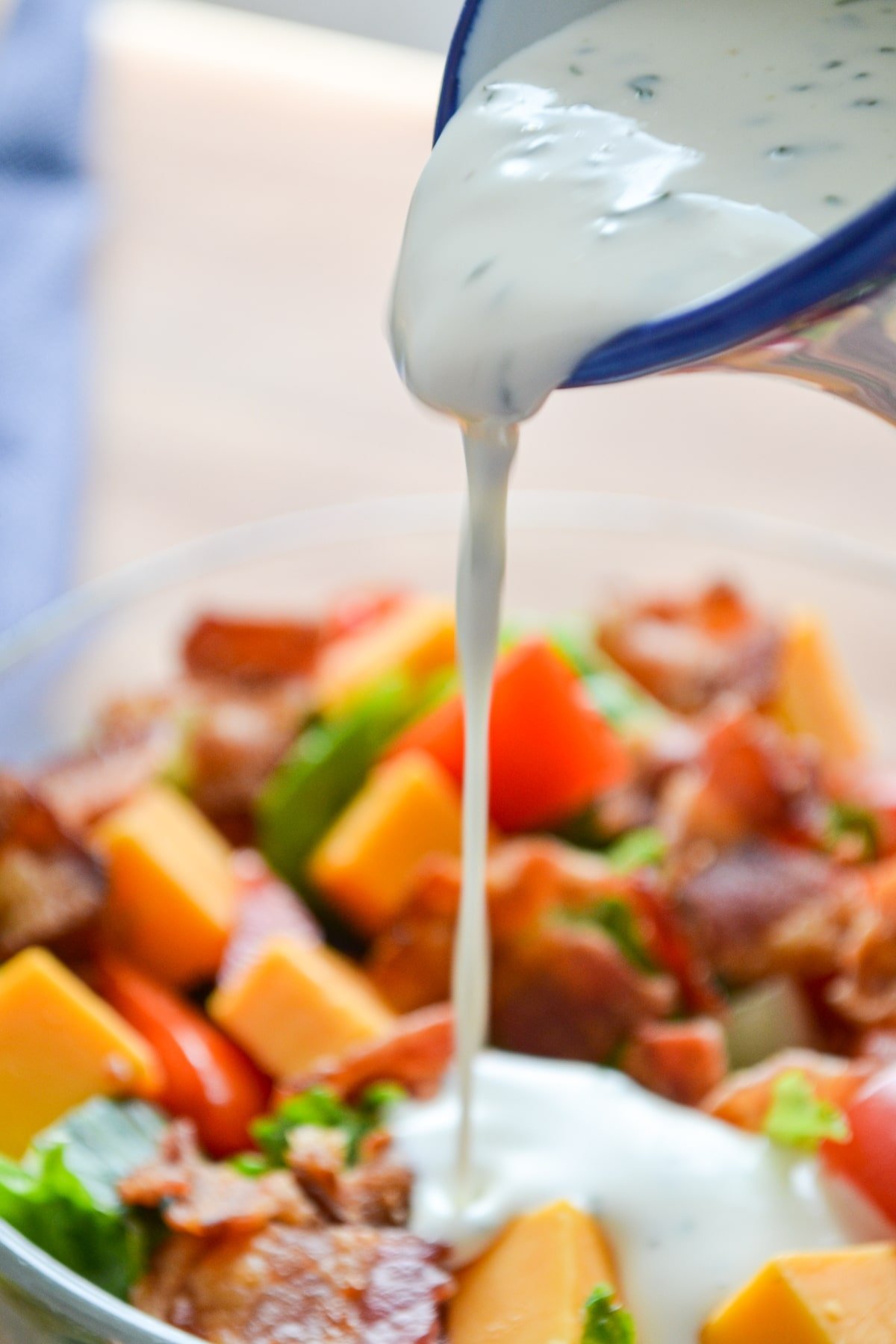 Buttermilk ranch dressing being poured onto BLT Salad