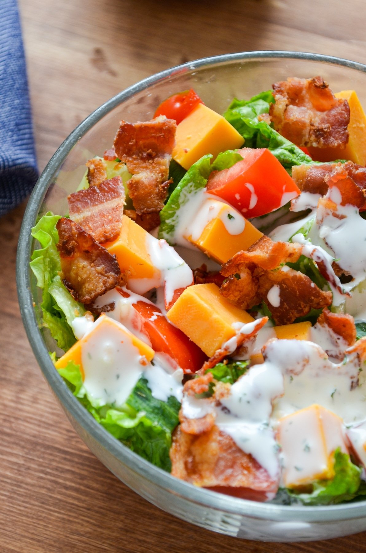 A bowl of salad, drizzled with buttermilk ranch dressing