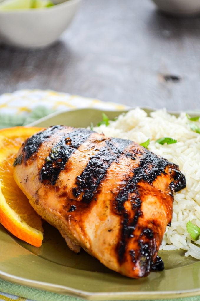 A close up of Grilled chicken on a bed of white rice.