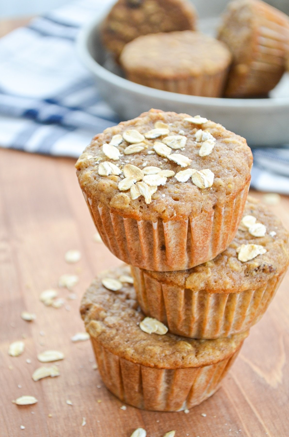 3 sourdough applesauce muffins stacked on top of each other with oatmeal sprinkled on top.