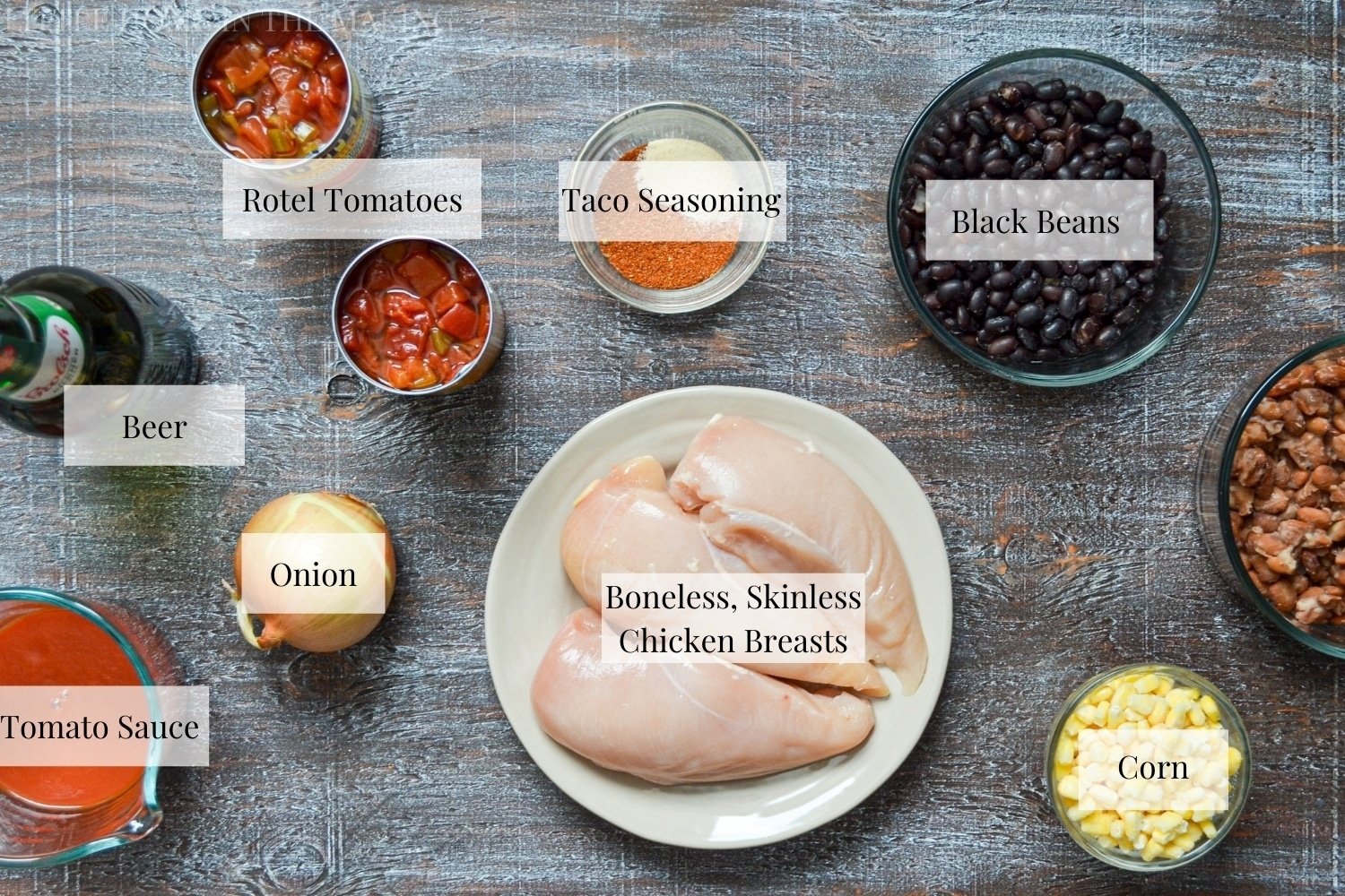 All of the ingredients needed to make chicken taco soup: chicken breasts, corn, tomato sauce, onion, black beans, taco seasoning, rotel tomatoes, and beer.